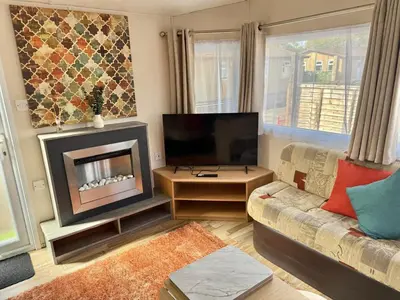 a living room with a couch and a fireplace at Deluxe Delta 4-Bedroom Caravan Located at Maryville Caravan Site Uddingston, Glasgow in Uddingston