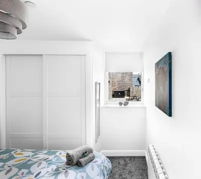 a white bedroom with a bed and a window at Castle Street Apartments - Luxury Kerrycroy Ground Floor Apartment in Rothesay