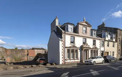 a white car parked in front of a large house at Castle Street Apartments - Luxury Kerrycroy Ground Floor Apartment in Rothesay