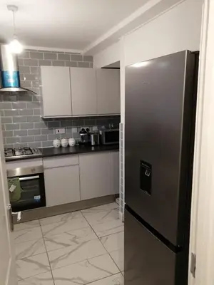 a kitchen with a stainless steel refrigerator and white cabinets at Modern 3-Bed Flat Stylish Family-Friendly in Moffat