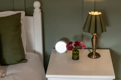 a table with a lamp and flowers on a bed at Kilmore Paws and Relax in Comrie