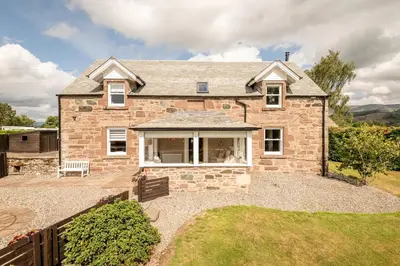 a large brick house with a yard at Kilmore Paws and Relax in Comrie