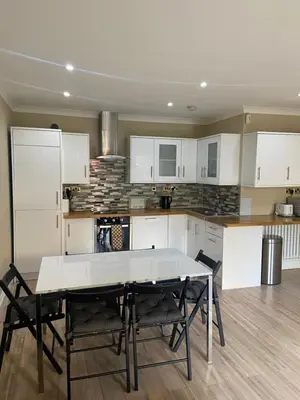 a kitchen with white cabinets and a table and chairs at Walker Apartment in Edinburgh