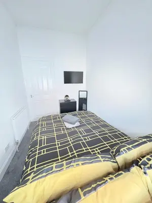 a bedroom with a bed with a yellow and blue blanket at 2Bed Gla Green, Walk Dist City Centre in Glasgow