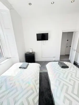 two beds in a room with a tv on the wall at 2Bed Gla Green, Walk Dist City Centre in Glasgow