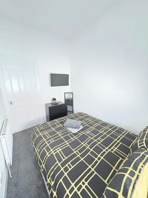 a bedroom with a bed with a yellow and black blanket at 2Bed Gla Green, Walk Dist City Centre in Glasgow