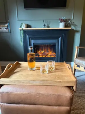 a bottle of whiskey and glasses on a table with a fireplace at Luxury Old Town Apartment just a 5 Minute Walk to Stirling Castle in Stirling
