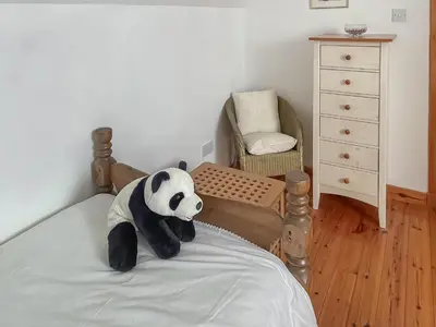 a stuffed panda bear sitting on a bed at Tigh An Droma Lodge in Whiting Bay