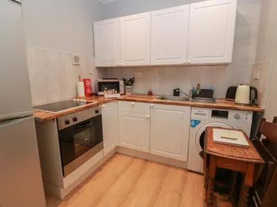 a small kitchen with white cabinets and a table at Cosy In in Millport