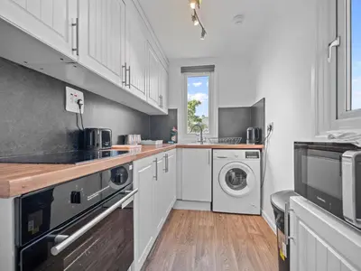 a kitchen with white cabinets and a washer and dryer at Ludgate 2 Bedroom Apartment - Alloa in Alloa