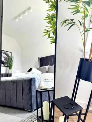 a bedroom with a bed and a mirror and a chair at Newtown Hideaway in Boʼness