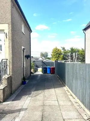 an alley between two houses with a fence at Newtown Hideaway in Boʼness