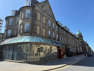 a large brick building with a store window on a street at City Centre Luxury Studio for 2 in Edinburgh