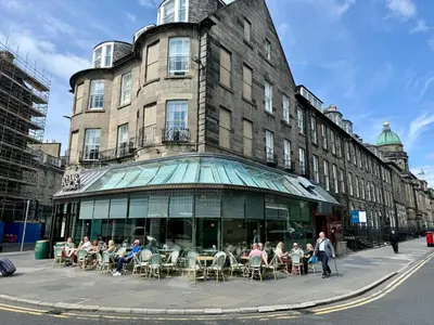 a group of people sitting at tables outside of a building at City Centre Luxury Studio for 2 in Edinburgh