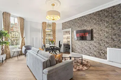 a living room with a couch and a tv on a wall at Prime Central Edinburgh 1 bed in Edinburgh