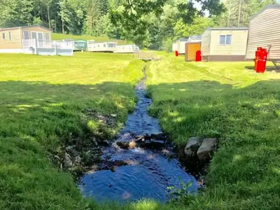 a stream in the middle of a yard with houses at Moffat Manor Holiday Resort in Beattock