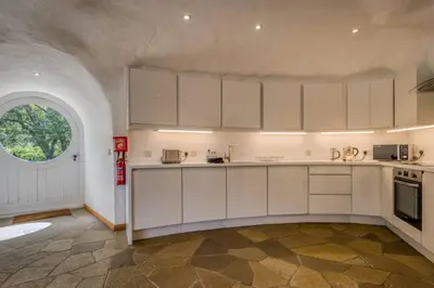 a kitchen with white cabinets and an arched window at The Warren - Hobbit House and Hot Tub at Loch Tay in Lawers