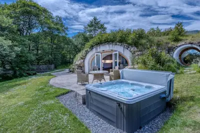 a hot tub in the backyard of a stone house at The Warren - Hobbit House and Hot Tub at Loch Tay in Lawers