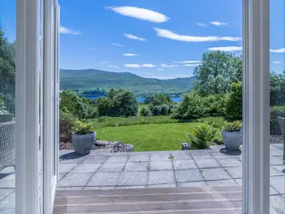an open door to a patio with mountains in the background at Loch Tay, Estate House with Panoramic Vistas in Lawers