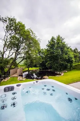 a large swimming pool in a yard with trees at Wishing Well Cottage at Loch Tay and Hot Tub in Lawers
