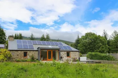 a house with solar panels on the roof at Sams Cottage with Loch Tay Vistas and Hot Tub in Lawers