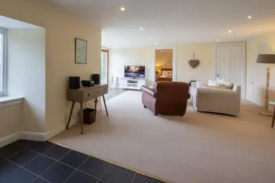 a living room with a couch and a chair at Sams Cottage with Loch Tay Vistas and Hot Tub in Lawers