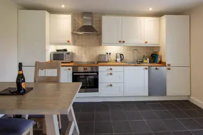 a kitchen with white cabinets and a wooden table at Sams Cottage with Loch Tay Vistas and Hot Tub in Lawers