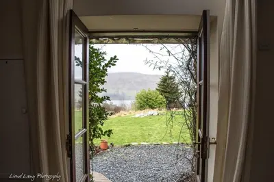 an open door with a view of a yard at Loch Tay Bothy Cottage with Hot Tub in Lawers