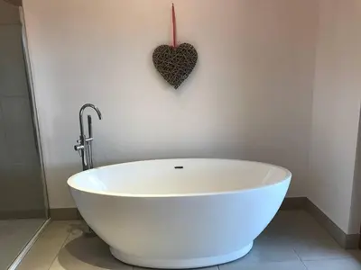 a white bath tub in a bathroom with a heart on the wall at Ben Lawers Rest Cabin - Hot Tub and Loch Tay Vistas in Lawers