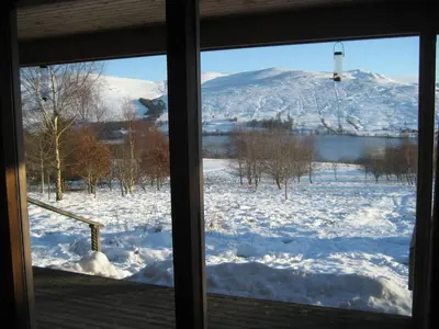 a view of a snow covered field from a window at Ben Lawers Rest Cabin - Hot Tub and Loch Tay Vistas in Lawers