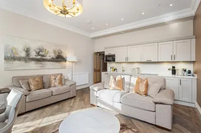 a living room with two couches and a kitchen at Prime Central Edinburgh 2 bed in Edinburgh