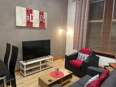 a living room with a couch and a television at Quirky Cottage Central Bathgate in Bathgate
