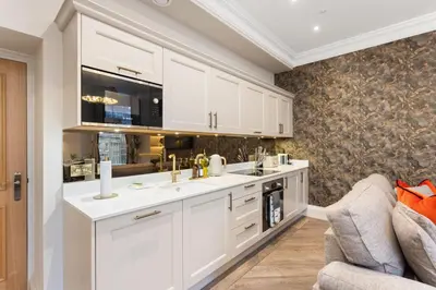 a kitchen with white cabinets and a couch at Prime Central Edinburgh 3 bed in Edinburgh