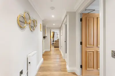 a hallway with white walls and wood floors and a gold door at Central Edinburgh Prime Luxury in Edinburgh