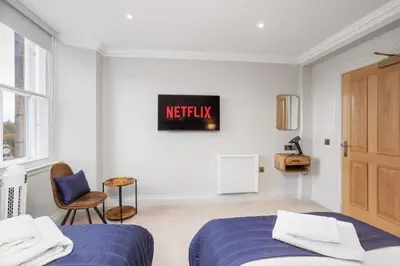 a white room with a bed and a chair at Central Edinburgh Prime Luxury 3 bed in Edinburgh