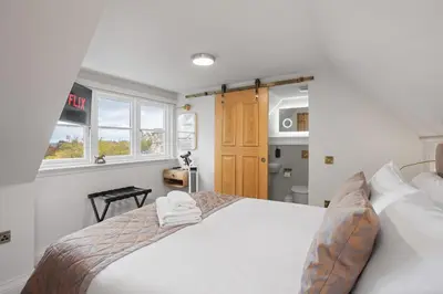 a bedroom with a white bed and a kitchen at Central Edinburgh Prime Luxury 3 bed in Edinburgh