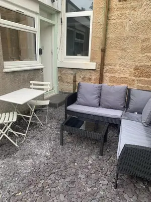 a patio with a couch and a table and chairs at Highland Hideaway Helensburgh in Helensburgh