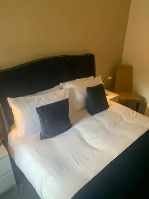 a white bed with two blue pillows on it at Highland Hideaway Helensburgh in Helensburgh