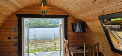 a door in a cabin with a view of a lake at Loch Leven Pods in Kinlochleven