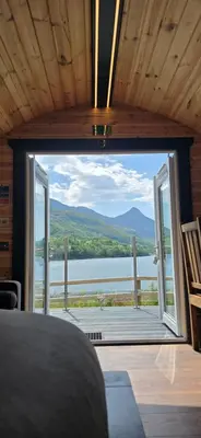 a room with a large window with a view of a lake at Loch Leven Pods in Kinlochleven