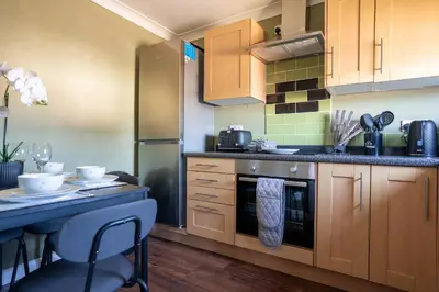 a kitchen with wooden cabinets and a table with chairs at Mercer Apartment in Alloa