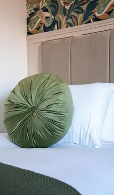 a green pillow sitting on top of a bed at Mercer Apartment in Alloa