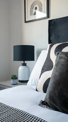 a bed with a black and white blanket and a lamp at Mercer Apartment in Alloa
