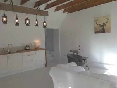 a white living room with a table and a kitchen at The Dairy Cottage, Loch Tay, Hot Tub and Garden in Lawers