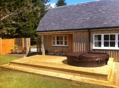 a large deck with a hot tub on a house at The Dairy Cottage, Loch Tay, Hot Tub and Garden in Lawers
