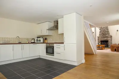 a large kitchen with white cabinets and a staircase at The Barn on Loch Tay - Hot Tub in Lawers