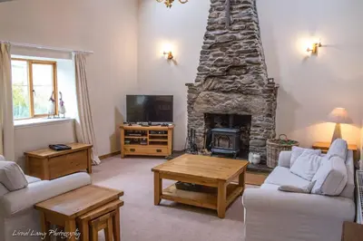 a living room with a stone fireplace and a tv at The Barn on Loch Tay - Hot Tub in Lawers