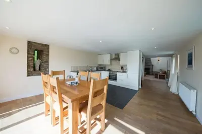 a kitchen and dining room with a wooden table and chairs at The Barn on Loch Tay - Hot Tub in Lawers
