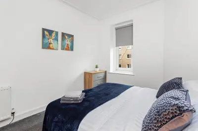 a white bedroom with a bed and a window at Stylish Stay in Inverkeithing. in Fife