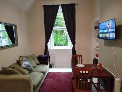 a living room with a couch and a table and a window at Lovely flat in Gorgie, Edinburgh in Edinburgh